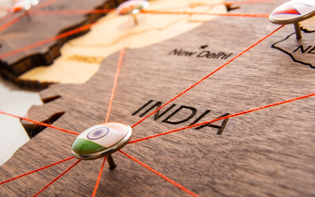 India flag on the pushpin and red threads on the wooden map, representing migration and diaspora